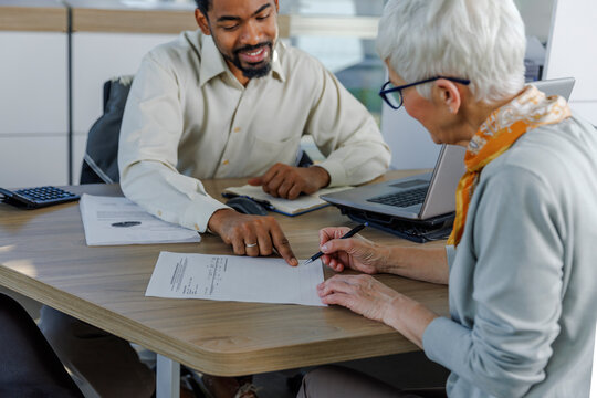 Smiling salesperson with customer doing paperwork at desk