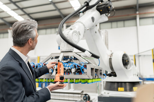 Businessman analyzing robotic arm in factory