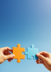 Two hands holding connecting orange and blue puzzle pieces symbolizing partnership on a clean sky background with copy space for business concept.