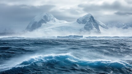 Dramatic seascape with snow-capped mountains and rough ocean waves under cloudy sky