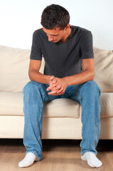 sad young man sits on a sofa with his head down
