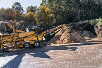 Industrial wood chipper processing tree branches and logs, creating sawdust, wood shavings, wood...