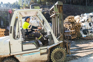Forklift operator managing waste materials at a recycling center, promoting environmental sustainability and resource recovery