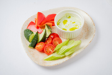 Crisp cucumbers, vibrant peppers, and cherry tomatoes with rich dip make a tasty snack