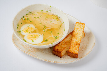 Savory chicken soup features tender meat and eggs, accompanied by crispy toasted bread
