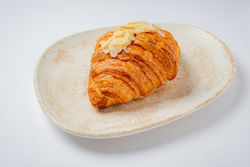 Golden-brown croissant topped with almond slices, showcasing its flaky texture inviting indulgence