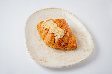 A delicious almond croissant sits elegantly on a rustic plate, inviting taste buds to indulge