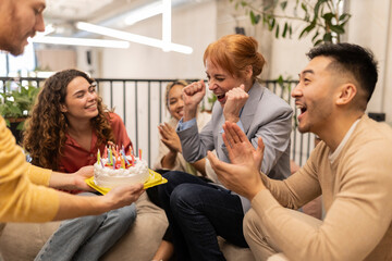 Happy colleagues celebrating birthday with businesswoman at office