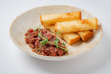 Juicy minced meat served alongside crispy toasted bread, garnished with fresh herbs for flavor