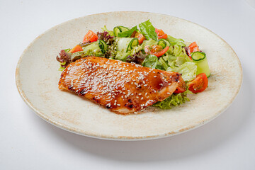 Tender grilled salmon topped with sesame seeds served alongside a vibrant garden salad
