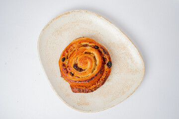 A scrumptious cinnamon roll with swirls of gooey goodness rests elegantly on a rustic plate