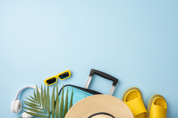 A composition featuring bright yellow travel accessories, suitcase, sunglasses, and hat on a pastel blue background, creating a fresh and summery travel theme