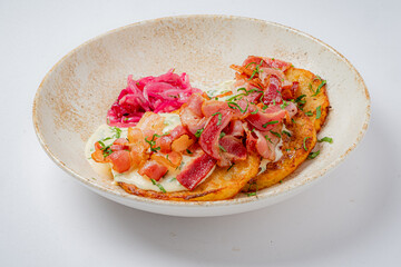 Crispy plantains are topped with diced tomatoes and onions, garnished with herbs on a rustic plate