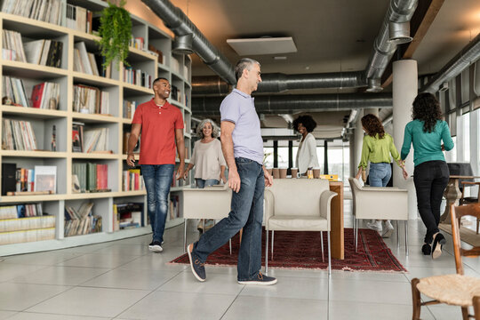 Happy business colleagues playing musical chairs at office