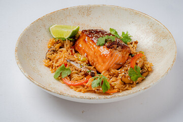 Delicious salmon glazed with sauce rests atop seasoned rice, garnished with fresh herbs and lime