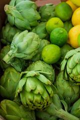Obraz premium Artichokes, limes, and lemons shine with color at a lively market