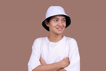 Young Asian Man Wearing White Bucket Hat And T-Shirt Smile Confidently While Crossed Arms