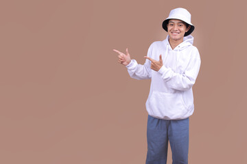 Asian Male in White Sweater and Bucket Hat Pointing Fingers To The Side for Mockup Ads