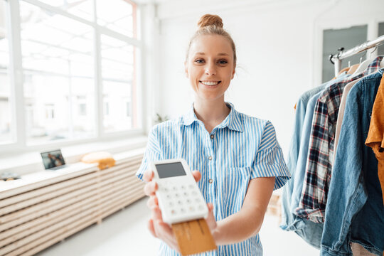 Smiling fashion designer holding credit card reader at studio
