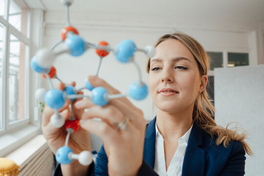 Beautiful businesswoman analyzing molecular model in office