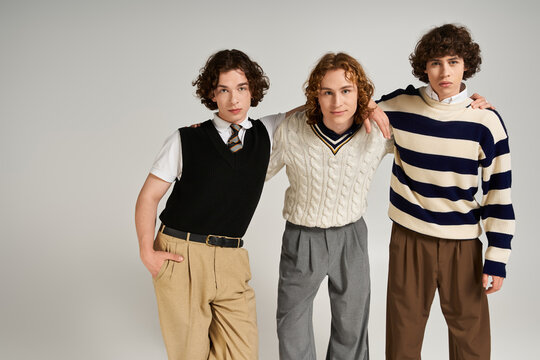 Stylish friends pose confidently in a studio, showcasing modern fashion