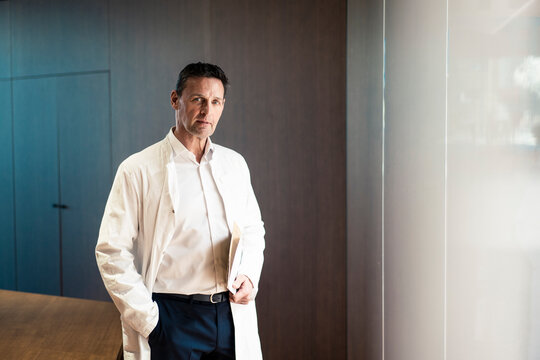 Confident doctor with hand in pocket holding file at hospital