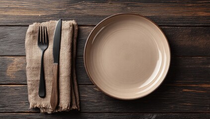 Empty plate, knife, and fork on a dark wooden table