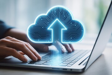 Cloud computing upload concept with glowing digital cloud icon over keyboard and hands on laptop on light background, symbolic of data technology.