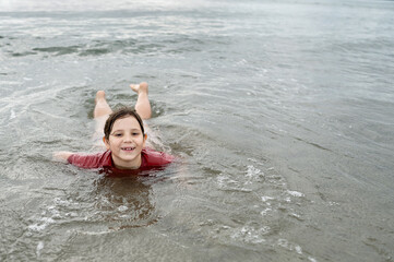 Smiling child girl swimming in sea water.