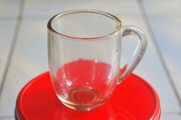Empty glass cup for espresso coffee isolated on red container.Without people.