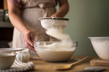 The woman sifts wheat flour, home baking