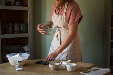 Woman using a digital tablet in the kitchen for cooking