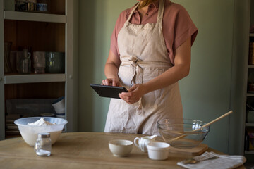 Woman using a digital tablet in the kitchen for cooking