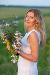 Woman holding a bouquet of wildflowers in a green field