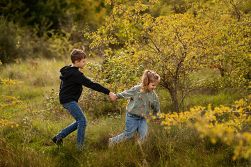 Fototapeta premium Sister and brother running through autumn park.