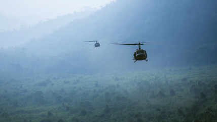 Helicopter flying above misty forest treetop, mountain background, early morning, calm atmosphere