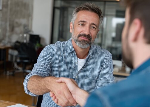 Business meeting happy businessman shaking hands with client in office environment