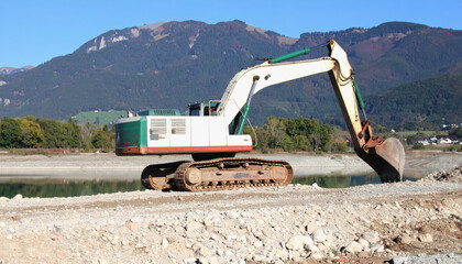 Construction site filled with heavy machinery and equipment amidst a natural landscape with copy space for text