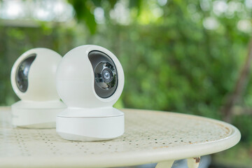 Home smart security camera on garden table. Surveillance tech for remote access video recording.