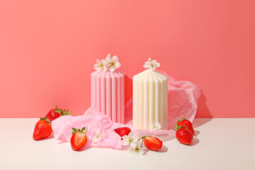 Colorful candles with floral accents sit next to fresh strawberries