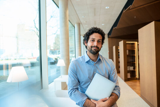 Smiling man with laptop in library