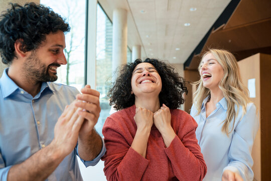 Happy woman celebrating success with colleagues in library