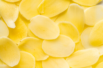 Slices of raw potatoes, thinly sliced to make chips. Background with the texture of raw potatoes. Close-up, top view