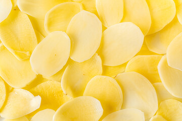 Slices of raw potatoes, thinly sliced to make chips. Background with the texture of raw potatoes....