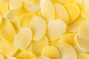 Slices of raw potatoes, thinly sliced to make chips. Background with the texture of raw potatoes. Close-up, top view
