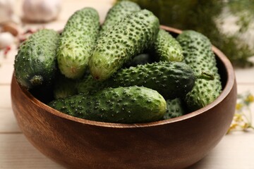 Making pickles. Fresh cucumbers in bowl on light wooden table, closeup