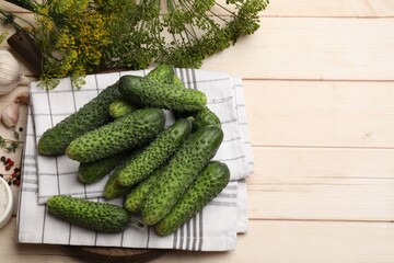 Making pickles. Fresh cucumbers, spices and dill on light wooden table, flat lay. Space for text