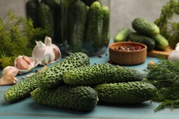 Making pickles. Fresh cucumbers and other ingredients on light blue wooden table, closeup