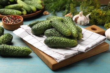 Making pickles. Fresh cucumbers and other ingredients on light blue wooden table, closeup