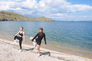 Women engaging in cardio training on a beach by a serene lake